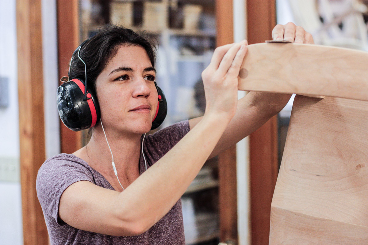 Audra hand sanding a rocking chair with 320 grit sand paper