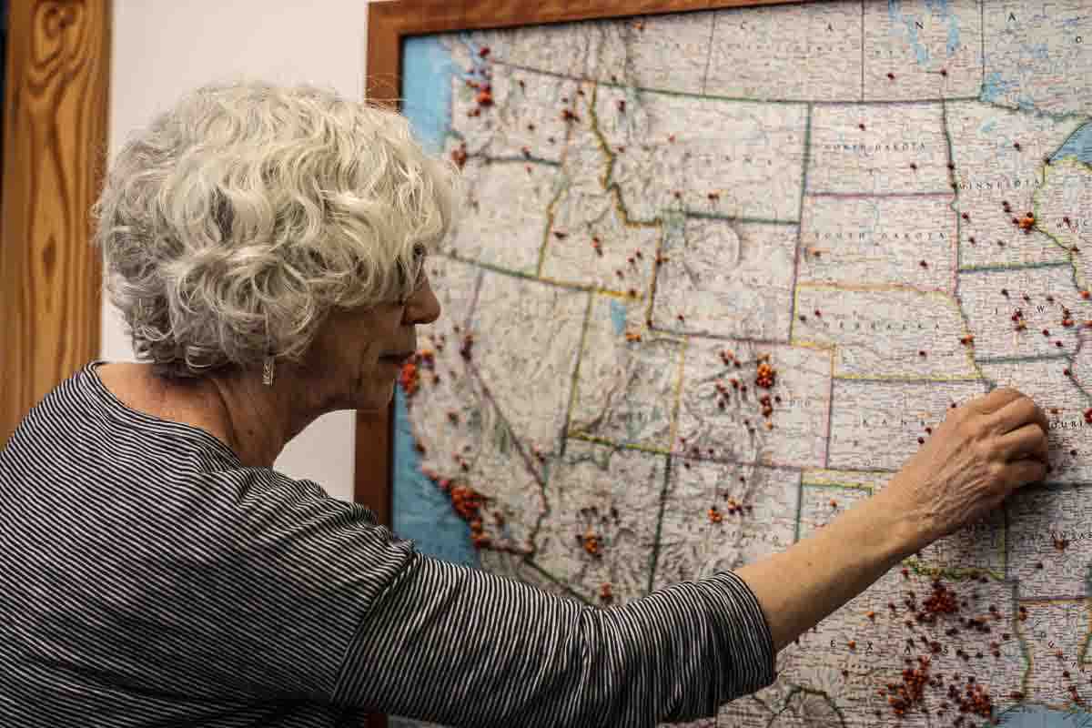 Leslie placing a pin in the map for a rocking chair patron