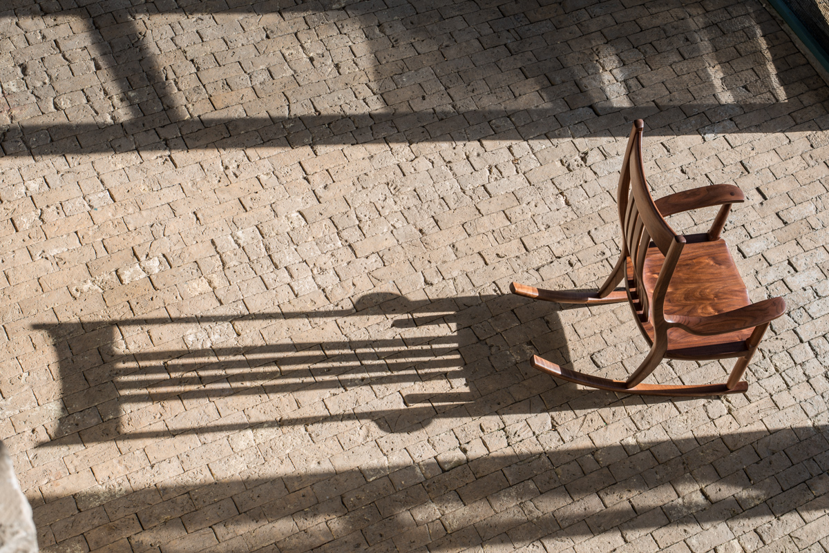 Walnut rocking chair in bright light with shadow.