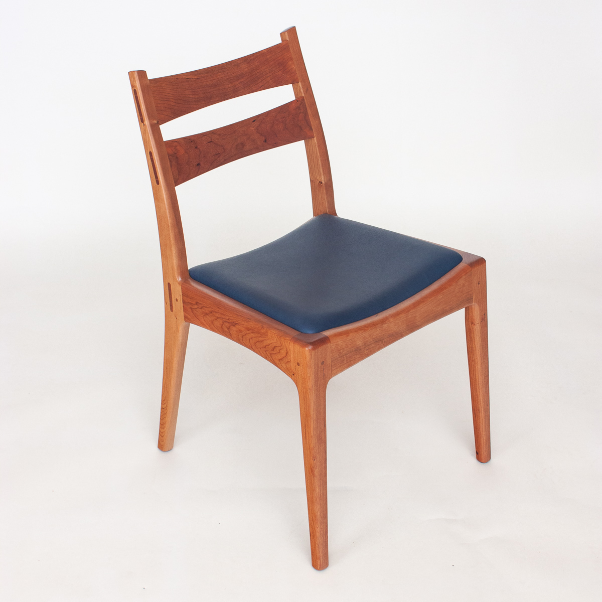 Our Webb Chair in cherry with a blue leather seat.  Front quarter view, showing crisp and supple lines and surfaces.