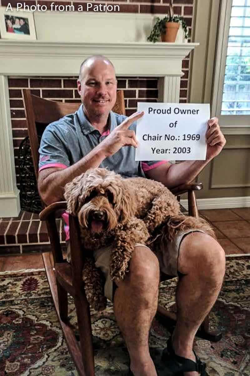 patron in rocker with sign, "Proud Owner..."