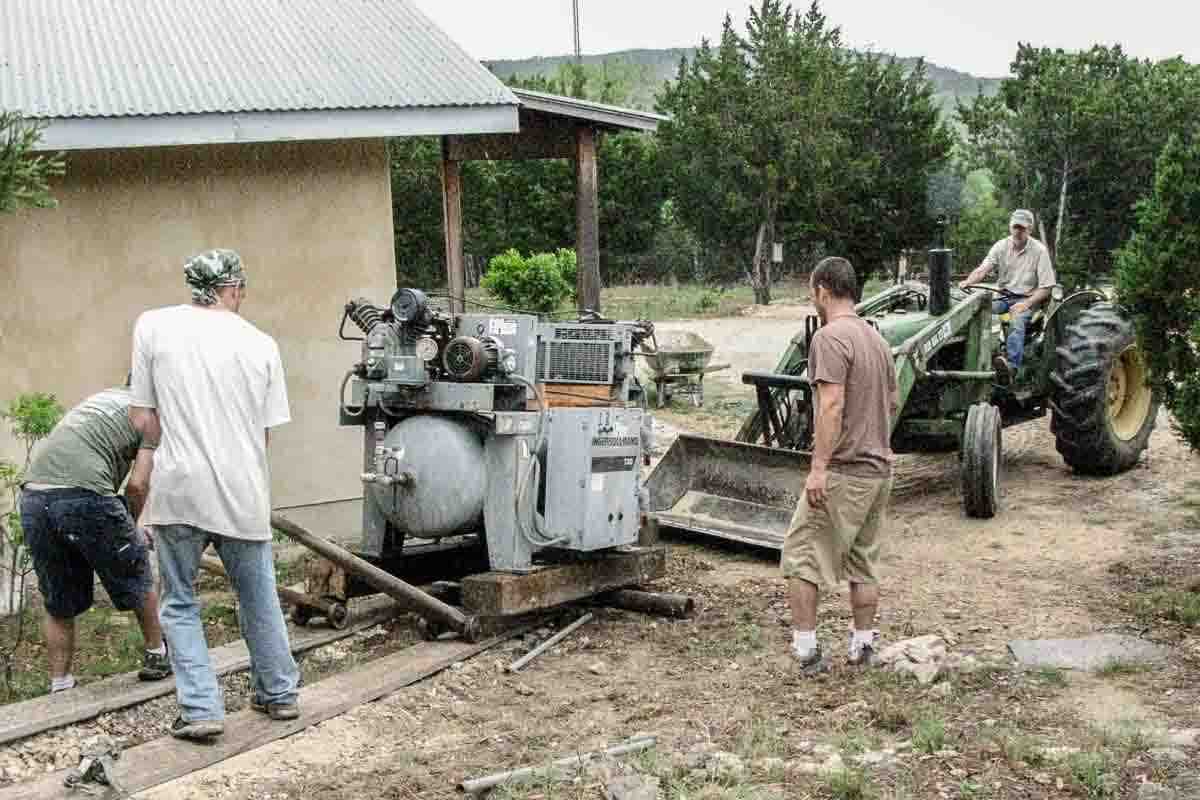crew moving air compressor up hill by hand 1