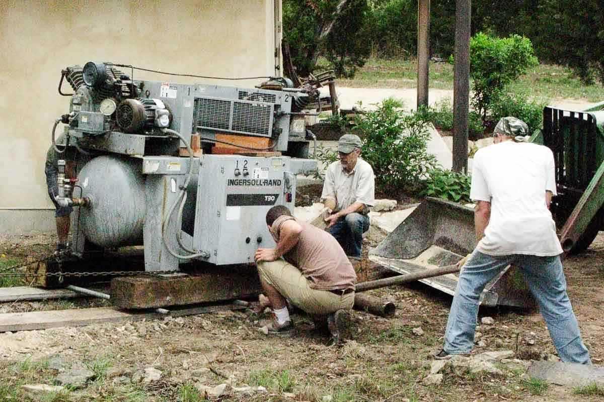 crew moving air compressor up hill by hand 2