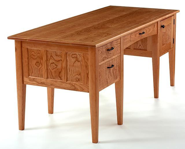 a cherry office desk in the studio, front quarter view.