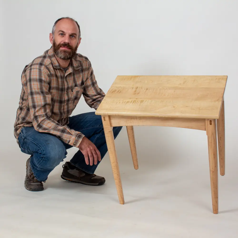Austin holding a maple Otwell Side Table in the studio.